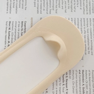 Detail of beige no-show socks with elastic edges on a printed magazine background