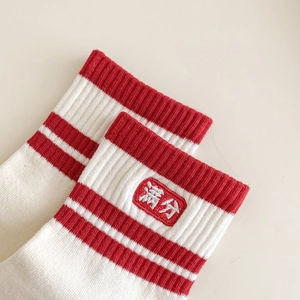 Détail de chaussettes en tricot avec rayures rouges et broderie de chance d'examen