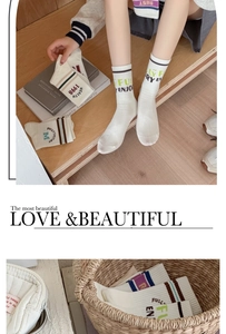 Detail of white cotton mid-calf socks with retro athletic stripes and varsity letters