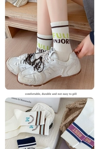 Detail of white mid-calf cotton socks with dark stripes and athletic lettering text