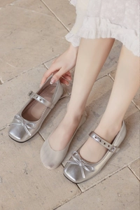 Detailed close-up of silver metallic Mary Jane flats with bow detail and square toe design