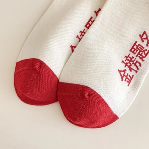 Macro détaillée de chaussettes en coton blanc avec pointe rouge et broderie chance