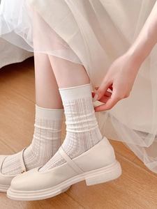 Détail de chaussettes en maille crème avec motifs en losange vintage et textures côtelées