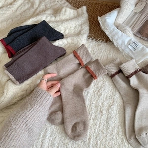 Detail of warm winter knit socks in earthy tones with ribbed cuffs on soft blankets