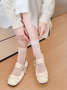 Gros plan de chaussettes en maille modale rose avec motifs losanges et chaussures Mary Jane