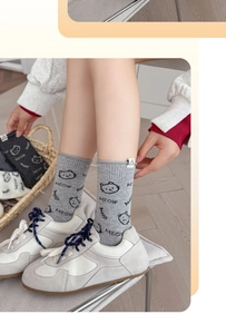 Detail of light gray knitted cat socks with fishbone pattern and Meow lettering