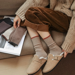 Close-up of cozy khaki faux suede clogs with thick sherpa lining and knitted crew socks