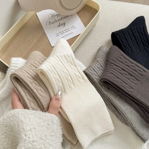 Detail of cable knit wool-like socks showing texture in multiple earthy neutral colors