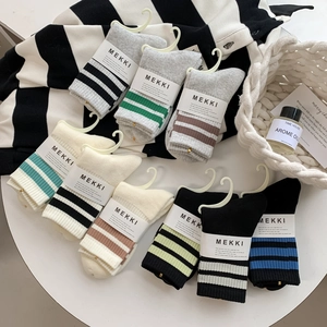 Close-up of striped cotton mid-calf socks in grey, beige, and black with brand packaging