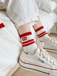 Gros plan de chaussettes en coton blanc respirant avec rayures rouges et broderie