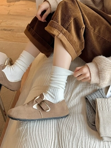 Detail of brown suede mule shoes with metal buckle paired with cozy knit socks