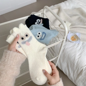 Close-up of thick winter socks with cute cartoon eyes and soft plush teddy fleece texture