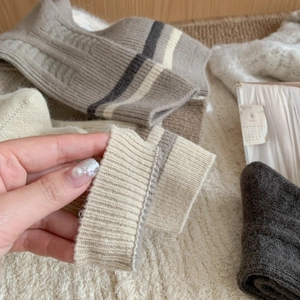 Close-up of thick striped wool socks featuring ribbed cuffs in neutral earth tones