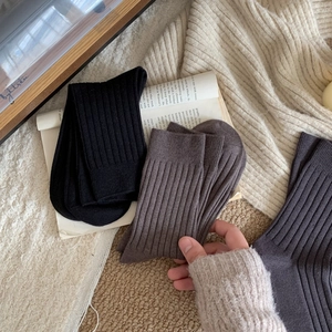 Detailed view of thick ribbed cashmere-like socks in black, brown, and charcoal grey