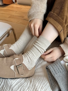 Detail of off-white knitted crew socks with thick ribbed texture for winter warmth