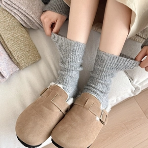 Close-up of thick grey ribbed wool socks paired with camel suede mule shoes for winter warmth