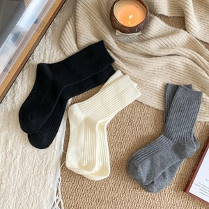 Cozy home setting with three pairs of ribbed knit crew socks in neutral tones