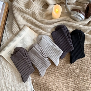 Four pairs of ribbed cashmere-style wool socks in neutral tones with cozy decor