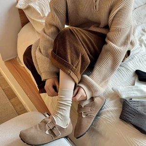 Close-up of brown suede sandals with buckle detail and beige ribbed knit socks