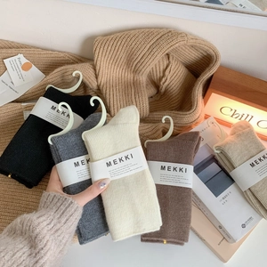 Five pairs of thick ribbed knit crew socks in neutral autumn colors with brand packaging