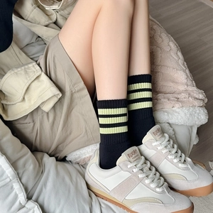 Macro shot of retro sneakers and black knit crew socks with neon yellow stripes