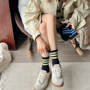 Detail of breathable cotton crew socks with neon stripes worn with sneakers