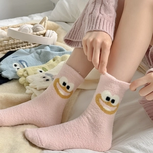 Close-up of pink fluffy camel hair socks with cartoon eyes for cozy winter warmth