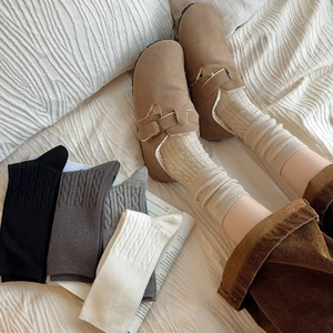 Close-up of thick cable knit texture on mid-calf wool socks in various neutral tones