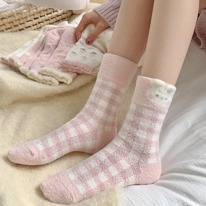 Gros plan de chaussettes en polaire corail à carreaux rose et blanc avec ornement lapin