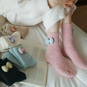 Detail showing plush coral fleece texture and knit bow decoration on cozy winter socks