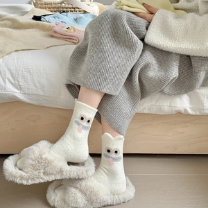Close-up of thick white camel wool socks with cute cartoon monster embroidery for winter
