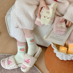 Primo piano di calze in pile con fragole e pantofole di peluche su pavimento