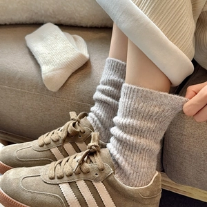 Thick grey knit wool crew socks for winter styled with vintage sneakers on a cozy rug