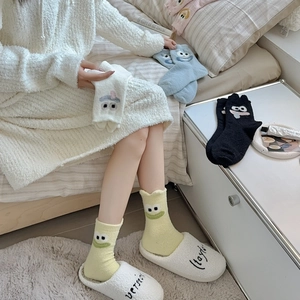 Detail of coral fleece thick socks with embroidered cartoon eyes and smiling faces