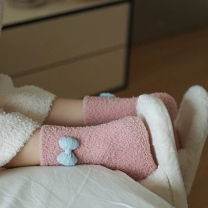 Detail of pink coral fleece thermal socks with blue bow knot and plush texture
