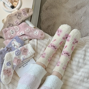 Gros plan de chaussettes d'hiver épaisses en polaire corail avec motif ours et texture douce