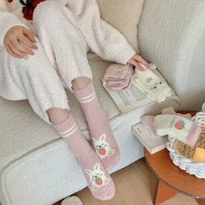 Dettaglio calzini in pile corallo rosa con ricamo di coniglio e fragola in primo piano