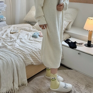 Close-up of yellow cartoon frog socks with cozy white fleece slippers in bedroom
