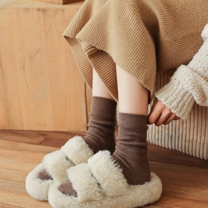 Detail of white plush open-toe slippers paired with dark brown ribbed knit socks