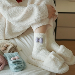 Detailed close-up of fluffy coral fleece socks with cute bowknot in a home setting