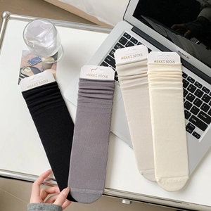Flat lay of four colorful ribbed cotton socks in black, gray, and white on a clean desk
