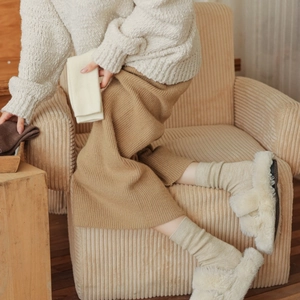 Close-up of thick knitted wool socks with white plush slippers in a cozy home setting