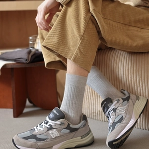 Detail of grey rib-knit crew socks paired with vintage suede sneakers and corduroy pants