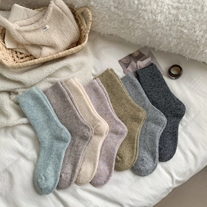 Detailed knit texture of seven colorful thick wool socks in a cozy home setting