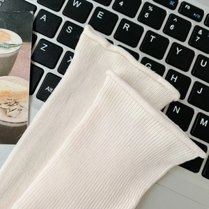 Macro view of cream knit vertical rib texture and rolled cuff on a stylish cotton sock