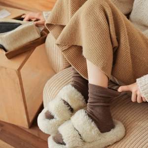 Close-up of brown ribbed thermal crew socks paired with plush slippers for home comfort