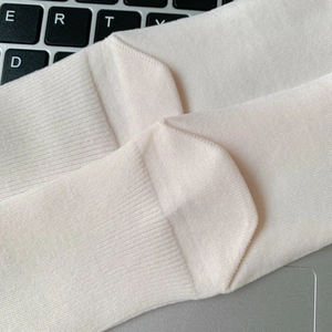 Close-up of reinforced heel stitching and fine knit texture on beige combed cotton sock