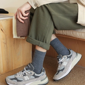 Detail of thick knitted ribbed mid-calf cotton socks in grey, brown and beige tones