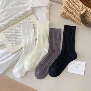 Detail view of four-color vertical cable knit mid-calf socks in minimalist style