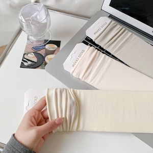 Close-up of ribbed cotton slouch socks in cream, pink, and grey with branded packaging